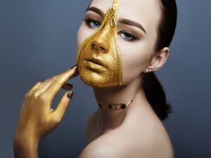 Creative grim makeup face of girl Golden color zipper clothing on skin. Fashion beauty creative cosmetics and skin care halloween. Brunette woman on dark background, beautiful big eyes and smooth skin