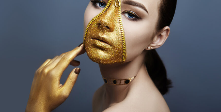 Creative grim makeup face of girl Golden color zipper clothing on skin. Fashion beauty creative cosmetics and skin care halloween. Brunette woman on dark background, beautiful big eyes and smooth skin